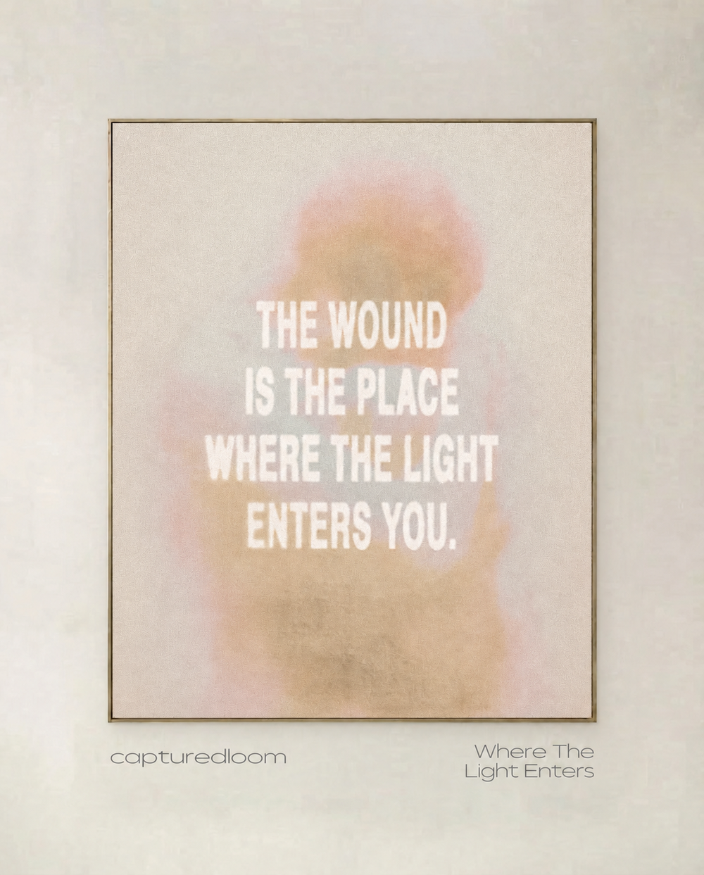 Where The Light Enters - typographic art print in soft blush and gold haze, shown in a thin gold frame on a pale wall